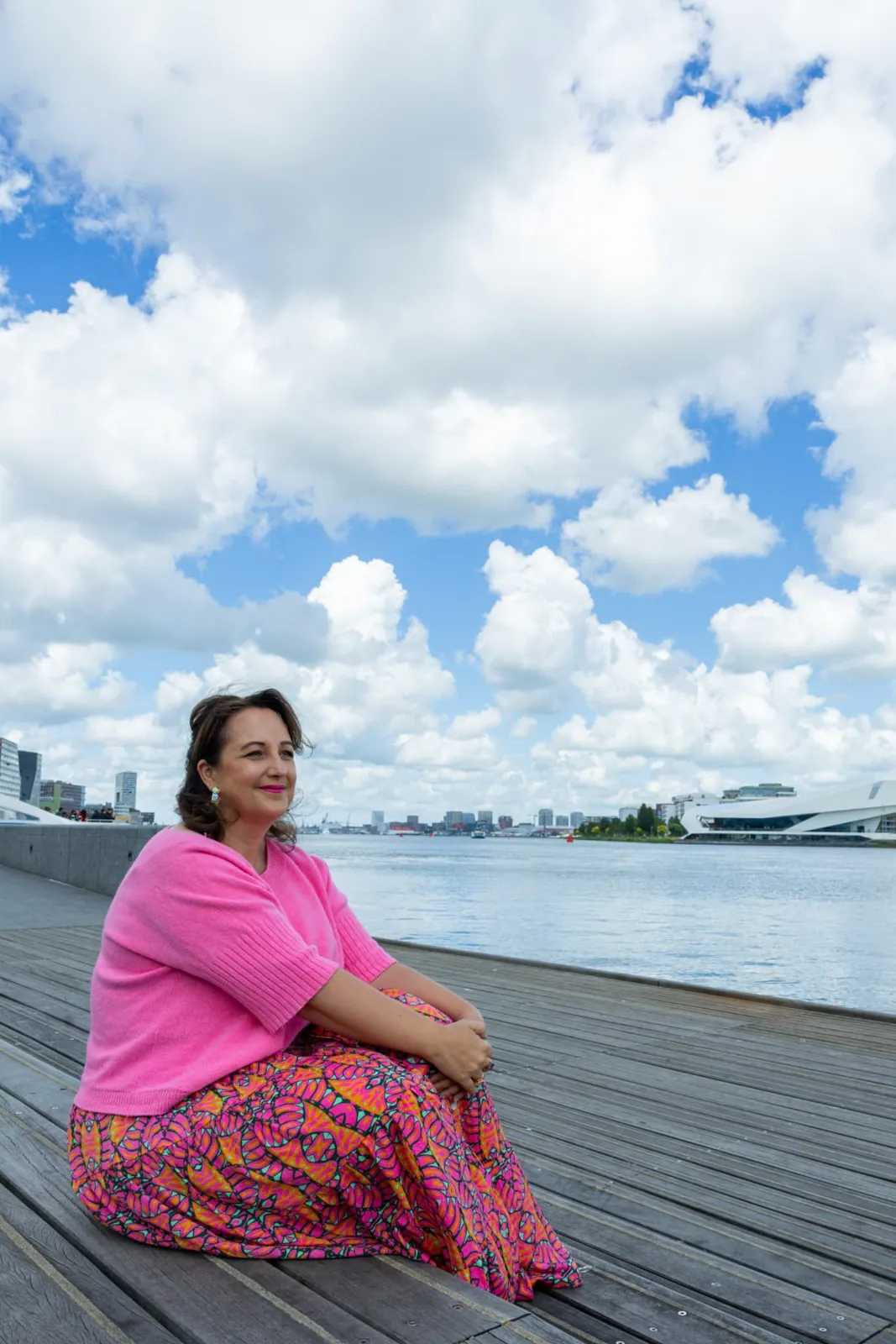 Raquel zit ontspannen aan het water onder een wolkenlucht